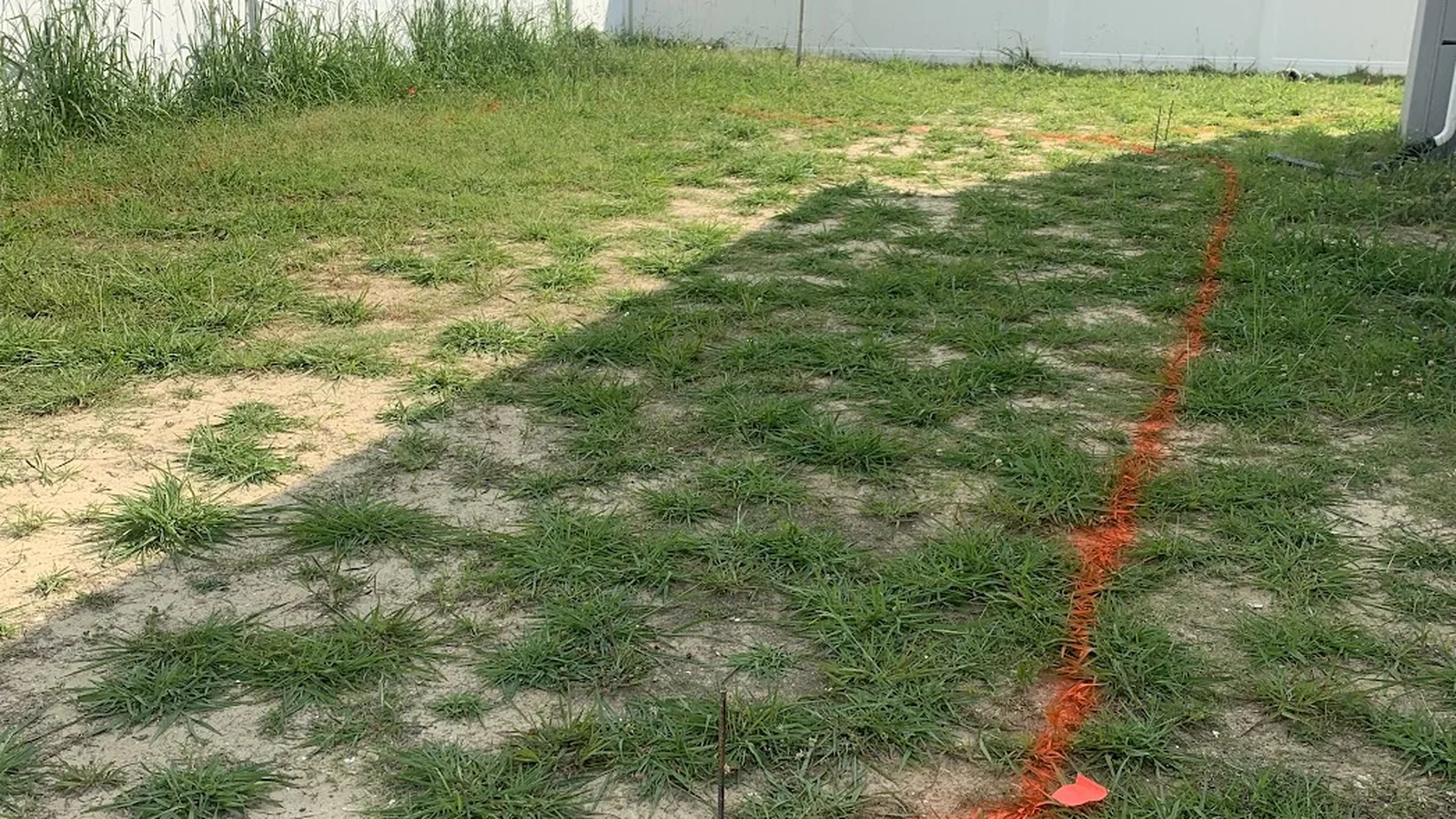 Earlier stage: patchy backyard turf marked for a new outdoor-living project